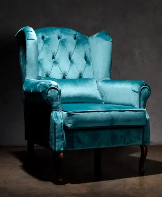 Sophisticated teal armchair in a dimly lit setting, highlighting Home Decor’s sofa upholstery services in Bahrain with a focus on leather and fabric reupholstery.