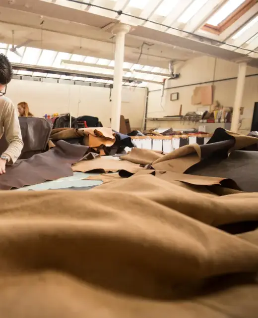 A craftsman working on premium leather upholstery in a well-equipped workshop. Highlights expertise in creating durable and elegant designs for sofas, chairs, and cushions in Bahrain.